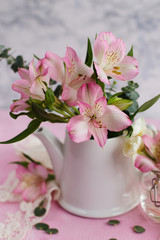 Pink flowers and herbs in the pot on a light background (close-up)