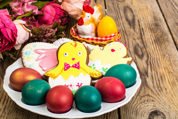 Fototapeta na wymiar Easter colored eggs and cakes with icing on white plate