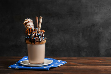 Milkshake, donut and other sweets in glass on wooden table