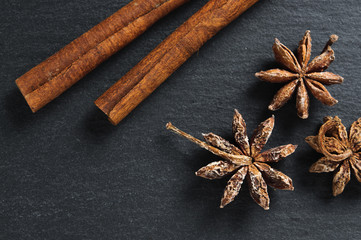 Ingredients: anise star and cinnamon sticks on black stone background. Top view