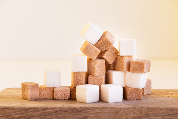 White and brown sugar cubes on wooden desk. Closeup. Copy space.