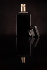 Dark, glass, elegeance bottle of perfume on a black background with mirror reflection made in photo...