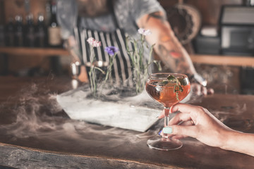 Beautiful girl is drinking a cocktail with ice vapor in the bar