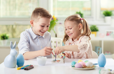 Obraz na płótnie Canvas Two happy children having fun during painting eggs for easter in spring