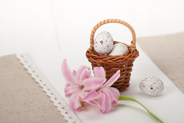 Fototapeta na wymiar Little Braided Wooden Basket With Chocolate Eggs On Handmade Natural Linen Napkin. Hyacinth Flowers