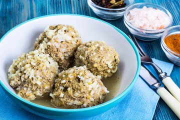 Meatballs meat with the rice grains in a blue ceramic bowl
