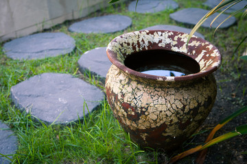 Old clay vase with water in the courtyard garden