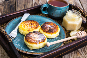 Pancakes with honey on vintage bowl on wooden tray