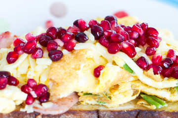 Close up of breakfast dish - omelette with green onion and ham, garnished with pomegranate