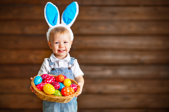 Happy Baby Boy In Easter Bunny Suit With Basket Of Eggs