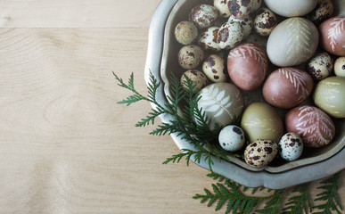 Hand-painted natural dye decorated Easter eggs in the vintage dish on a wooden background. Empty space for your promotional content. Easter concept