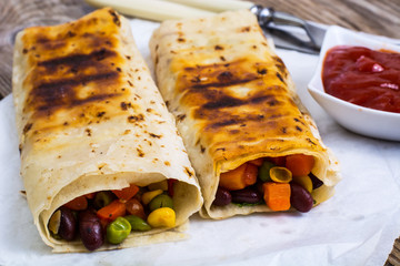 Pita with corn, beans, peas, carrots on background of old boards