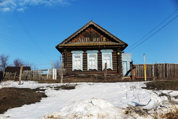 Old log house in the remote Russian village in the early spring against a blue sky