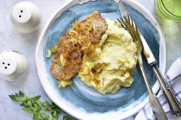 Fried pork chop with caramelized onion garnished with mashed potato.Top view.