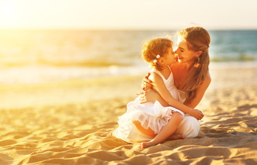 happy family at beach. mother hugging baby daughter at sunset