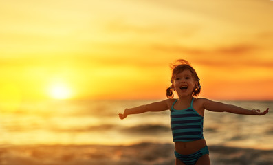 Happy child girl in bikini on beach in summer sea