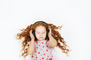 Curly little girl listening to music on headphones.