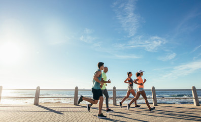 Group running along a seaside promenade - Powered by Adobe