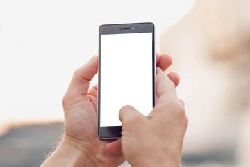 Making photo outdoors by smartphone. Hands holding and touch on blank smartphone with clipping path for screen.