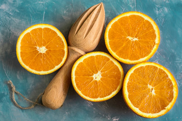 Fototapeta na wymiar Composition of bright colorful ripe oranges cut in half with wooden reamer on blue background, top view