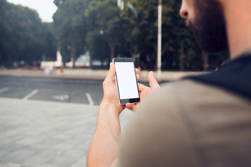 Phone with blank screen in hands, over the shoulder view. Shot with third-person view. Clipping path for screen.