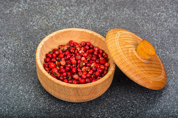 Dried pink pepper peas in a wooden bowl on gray background