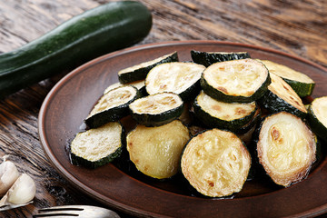Fried zucchini in a clay plate on a wooden table