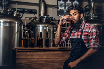Indian male manufacturer tasting craft beer in the microbrewery.