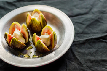 Figs with whipped cream and honey against black background. Concept of cooking and eating healthy food, fitness, vegetarian and vegan, and lifestyle.