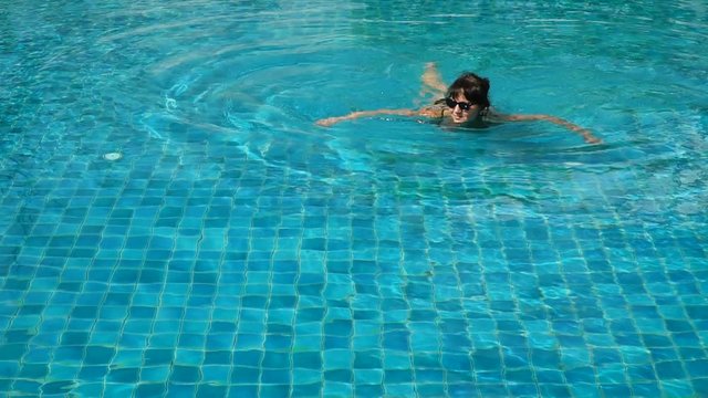  Slow motion video of a happy woman relaxing and swimming in the swimming pool
