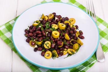 Salad with red beans and green olives in bowl on white boards