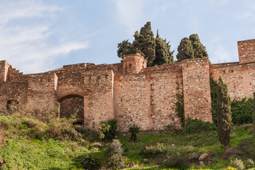 Medieval stone arches, walls and towers of an ancient Alcazaba fortress in Malaga, Spain.