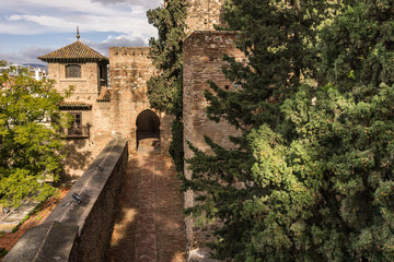 Fototapeta na wymiar Medieval stone arches and walkway by the walls and towers of an ancient Alcazaba fortress in Malaga, Spain.