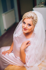 Portrait of young beautiful bride in elegant pink robe 