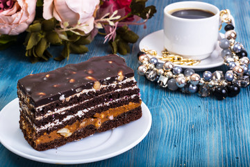 Chocolate sponge cake with caramel and nuts on blue background