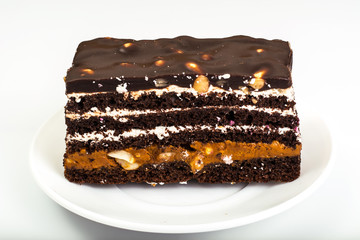 Chocolate caramel cake with nuts and whipped cream on white back