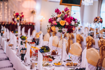 Wedding flower composition for guests and newlyweds tables. Wedding arch and flowers decor.