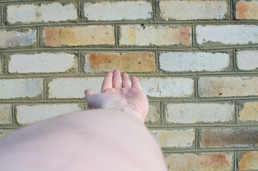 palm of the hand of an adult male stretching into the distance on a background of a brick wall