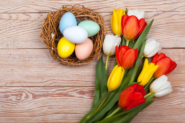 Obraz na płótnie Canvas Easter Eggs in a birds nest with colorful tulips