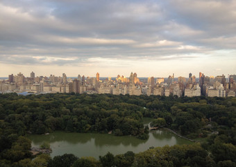 Fototapeta na wymiar The Lake in Central Park, New York, viewed from a tall building on the west side of the park.Aerial view of Central Park, sun setting on Upper East Side apartment buildings.Overview of Central Park.