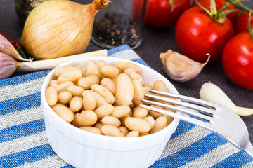 Canned beans with olive oil and garlic in white salad bowl