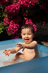 Fototapeta na wymiar cute happy little kid splashing in the pool in the garden