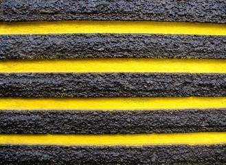 Detail of black and yellow striped concrete wall background texture.