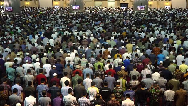 Rear view of devout muslim men praying together on the Friday prayer time in mosque