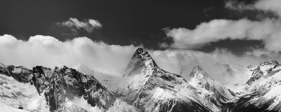 Black and white panorama of snowy mountains in clouds