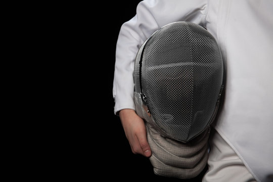 Fencer woman hold her helmet in hand wearing white fencing costume. Isolated on black background.