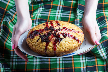 A woman holds a pie with sweet sauce of berry jam. Sweet Banana Bread with blueberry confit. Simple...