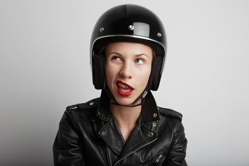 Portrait of biker woman over white background, female with funny face wearing stylish black...