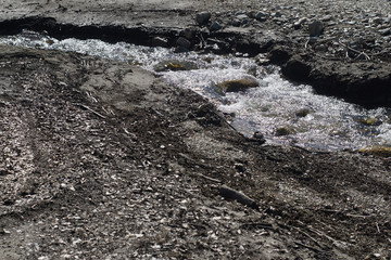 Mountain stream surrounded by pebbles, sand and dry leaves