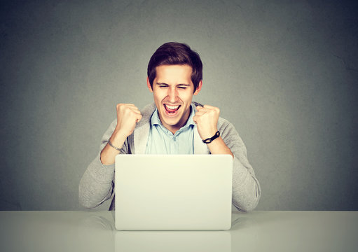 Man celebrating success in front of a laptop